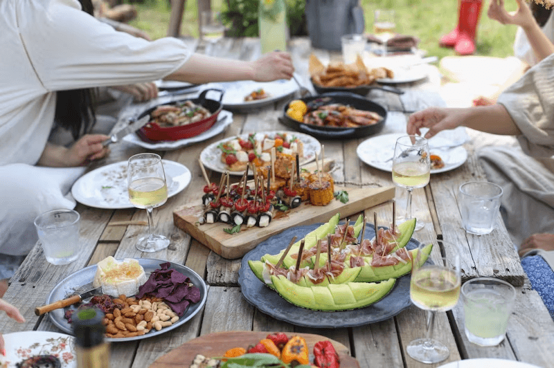 an outdoor food table with a variety of dishes
